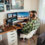 a person sitting at a desk with a computer and headphones on